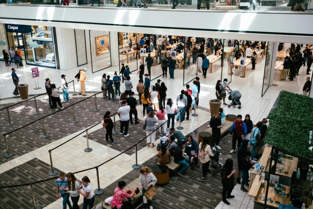 pexels photo 13753893 13753893 A bustling shopping center with a large crowd queuing inside an Apple Store.